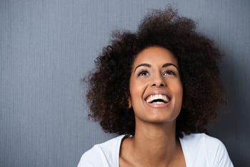 Laughing African American woman with an afro hairstyle and good sense of humor smiling as she tilts her head back to look into the air